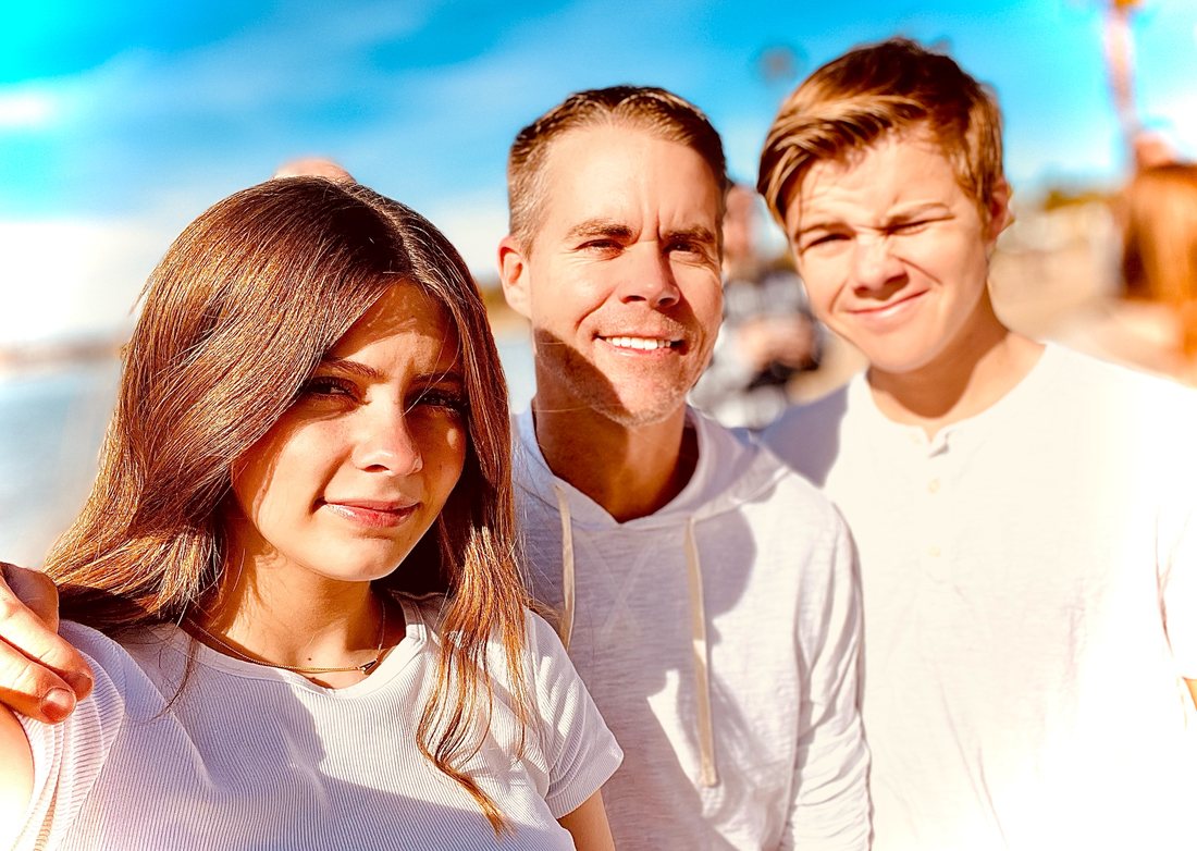 Jason smiling outdoors with his two teenage children